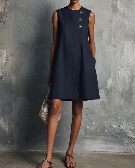Vestido mini de mujer de estilo minimalista y profesional, de color azul marino, con cuello redondo, botones asimétricos, bolsillo lateral y sin mangas.